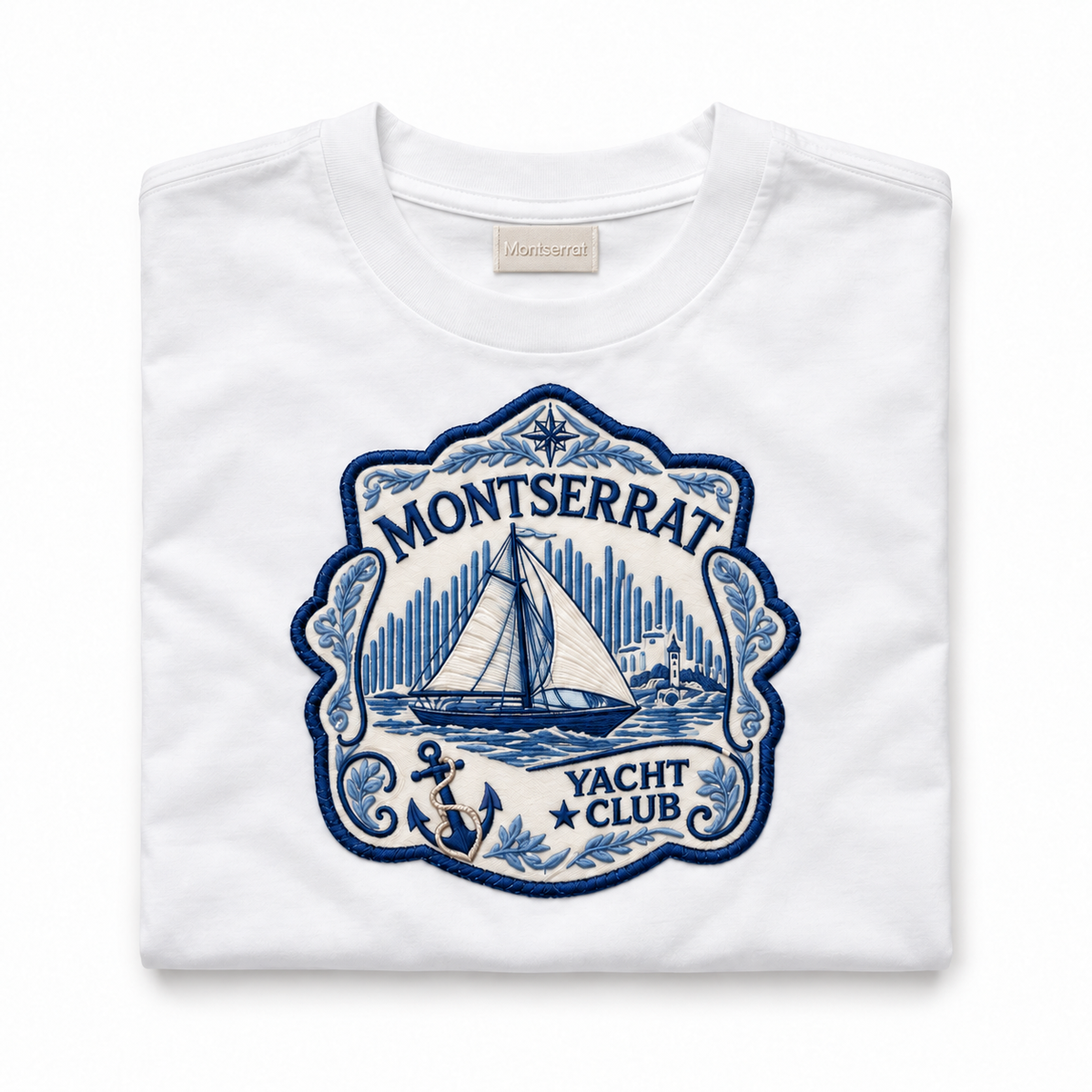 A folded white crewneck t-shirt with a large blue embroidered patch on the front reading 'Montserrat Yacht Club' with a sailboat illustration.