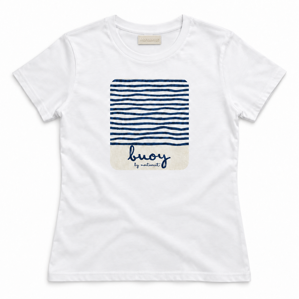 A white short-sleeve crewneck t-shirt by Montserrat, featuring a central graphic print of navy blue horizontal stripes on the top half and a cream-colored bottom half with the brand name 'buoy by Montserrat' written in navy script.